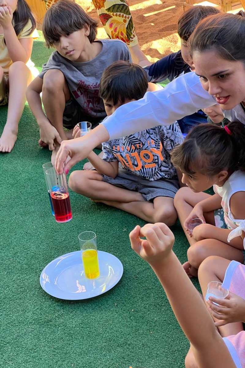 Crianças observando experiência com copos coloridos