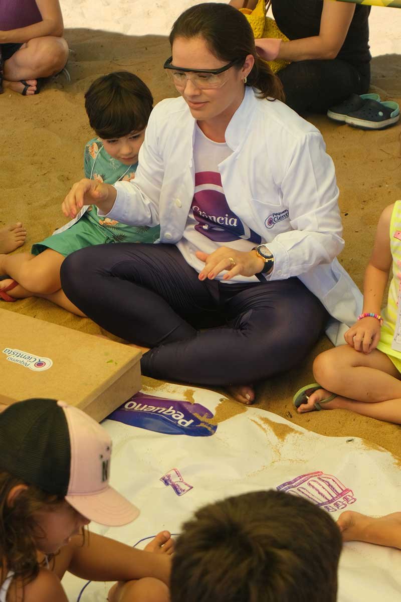 Professora aplicando experimento com crianças sentadas no chão